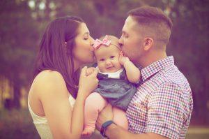 Parents holding and kissing their baby girl. 