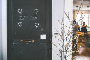 A black door with the word bonjour written on it, which you will see a lot after moving home to Montreal.