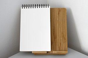 A white notepad on a brown paper stand. 