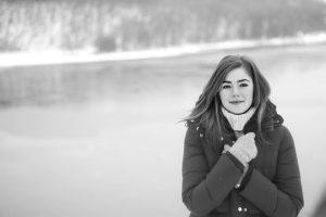 A black and white picture of a woman in a winter jacket. 