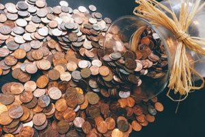 A jar with lots of coins spilled out of it. 