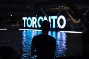A silhouette of a man in front of the Toronto sign. 