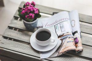 A magazine and a cup of coffee on the table.