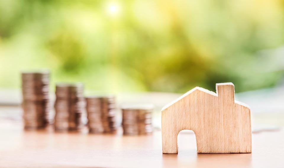 Stacks of coins next to a small house, to help pay deposits for your move.