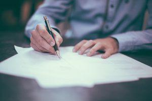 A man holding a pen, that can help you change your address before you move.